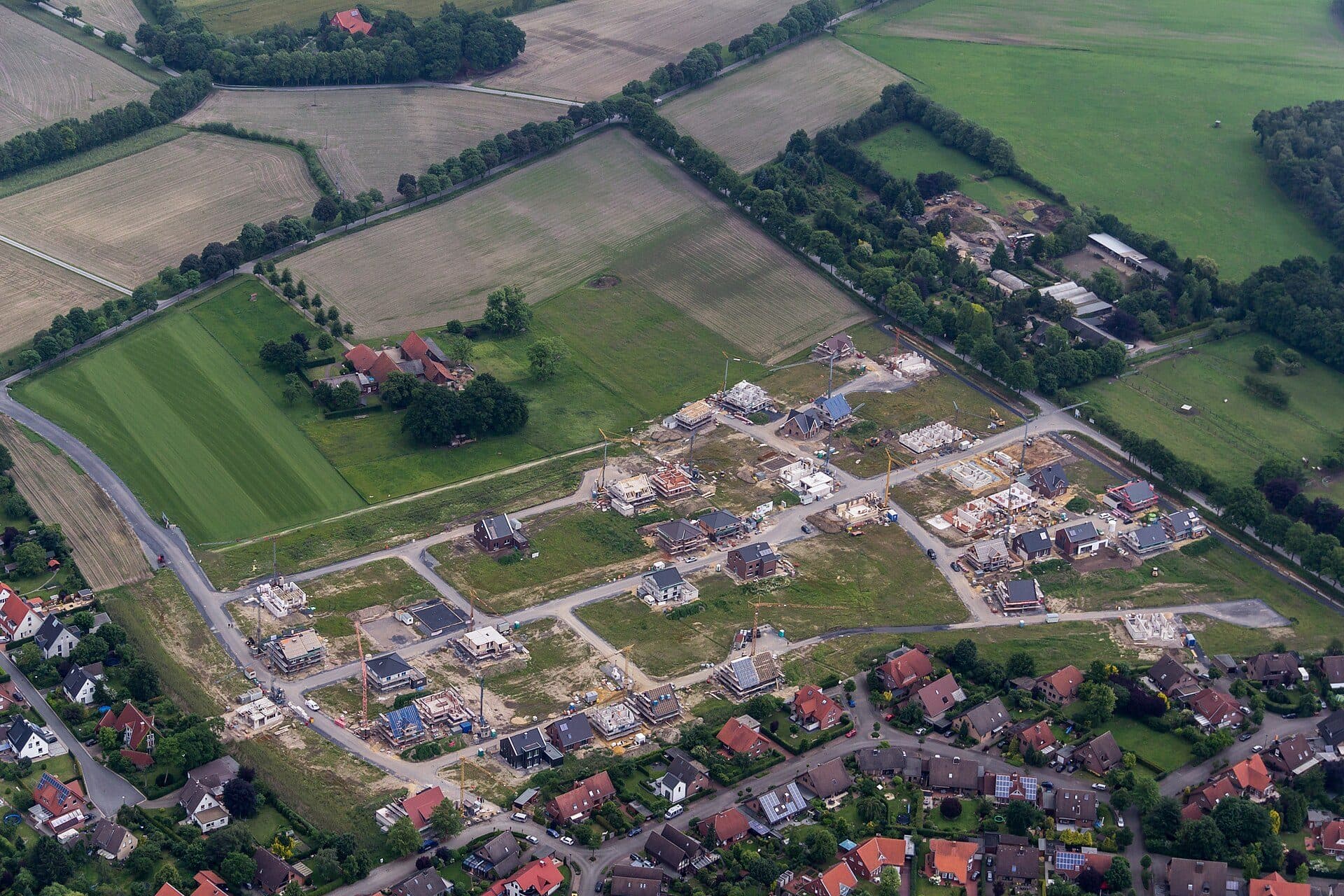Senkrechtes Luftbild eines Neubaugebiets mit angrenzenden freien Feldern, Wegen und Wohnbebauung